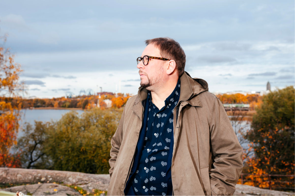 Paavo Arhinmäki syksyisellä Töölönlahdella. Arhinmäki seisoo kalliolla ja katsoo vasemmalle.