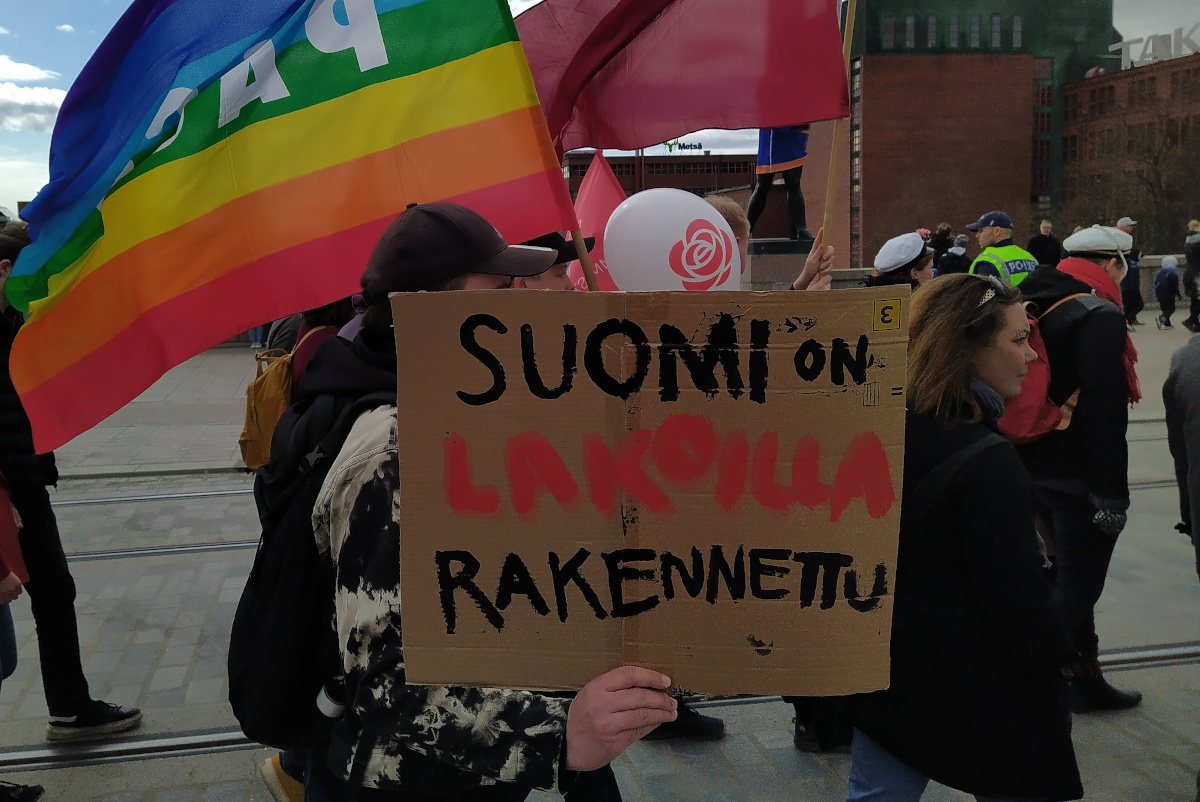 Vappukulkueeseen osallistuva ihminen kantaa kädessään kylttiä, jossa lukee "Suomi on lakoilla rakennettu".