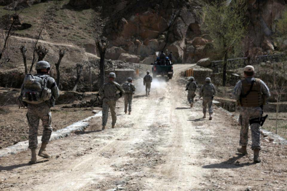 Mustavalkoisessa kuvassa sotilaita kulkemassa tiellä.