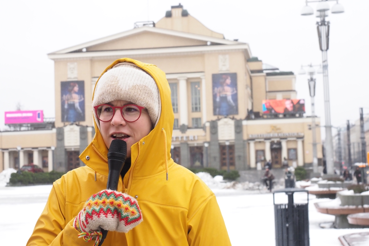 Hanna Sarkkinen keltaisessa takissa puhumassa mikrofoniin torilla.