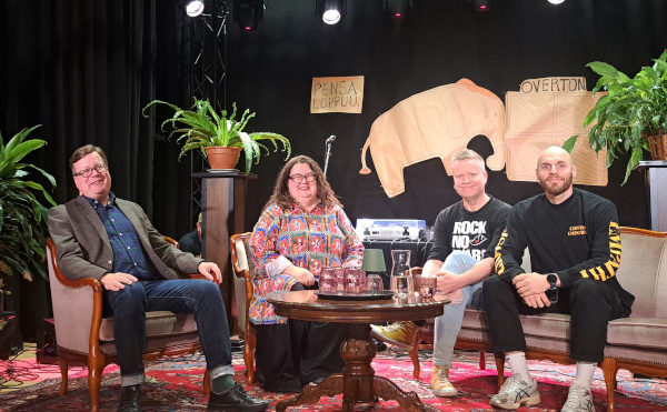 Panelisteja istumassa näyttämöllä.